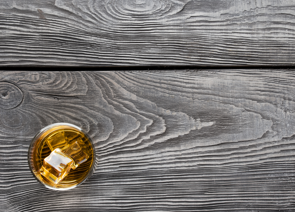 Wooden background with a glass of whiskey with ice. Wooden background with a glass of whiskey
