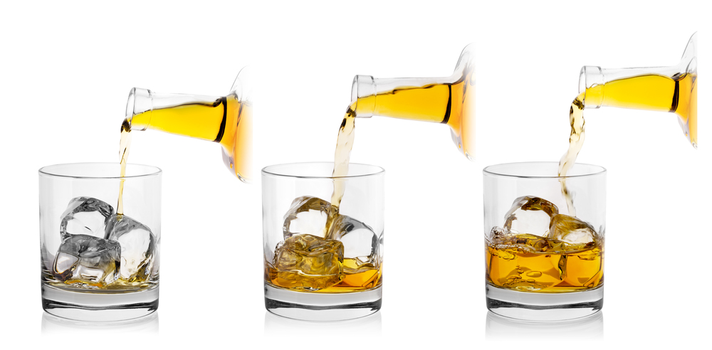 The process of pouring whiskey from bottle into glass with ice. Isolated on white background. Collage.. The process of pouring whiskey from bottle into glass
