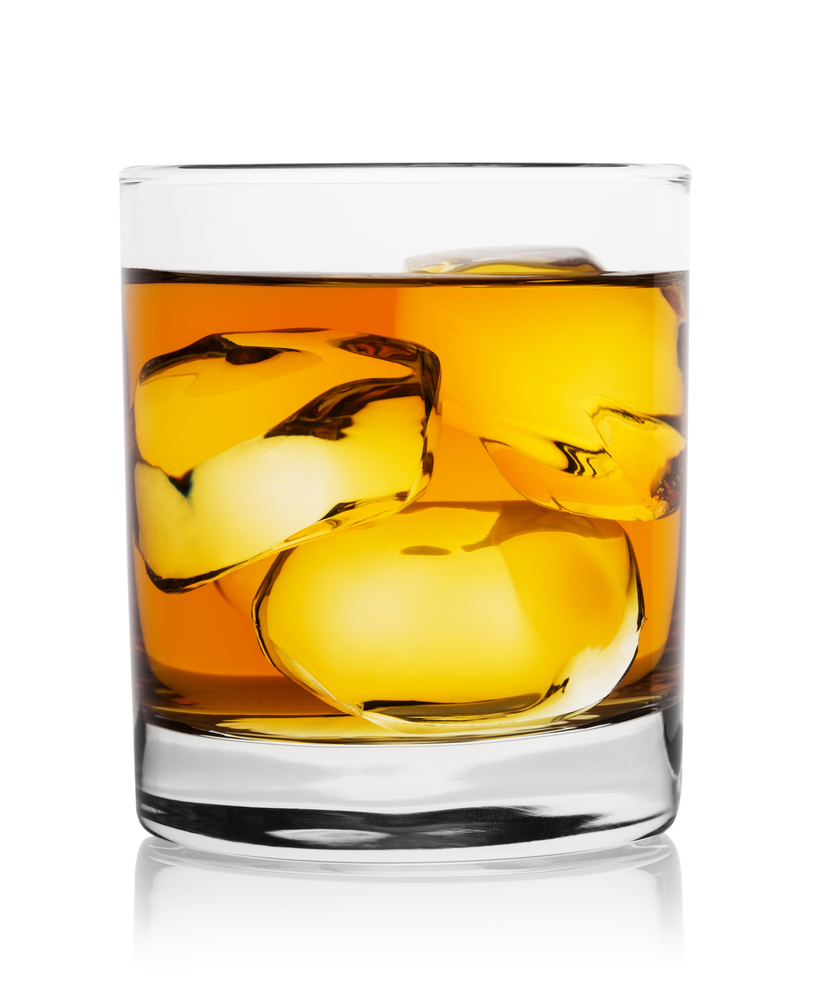 Translucent gold whiskey with ice cubes in glass and his reflection isolated on white. Translucent gold whiskey with ice cubes in glass