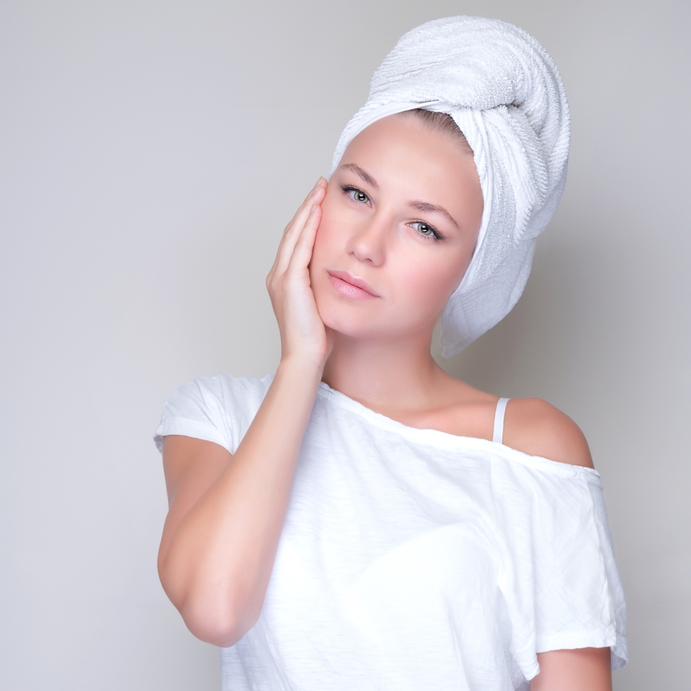 Closeup portrait of beautiful young woman with towel on head isolated on gray background, enjoying day spa, beauty treatment concept