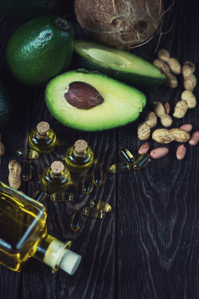 source of omega 3. Oil of avocado with fish oil pills and peanut - source of omega 3 on a dark wooden background