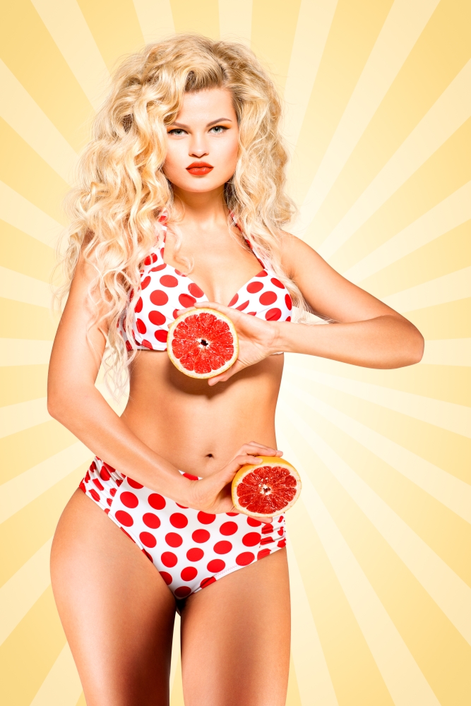 Beautiful pinup bikini model, holding a grapefruit on colorful abstract cartoon style background.