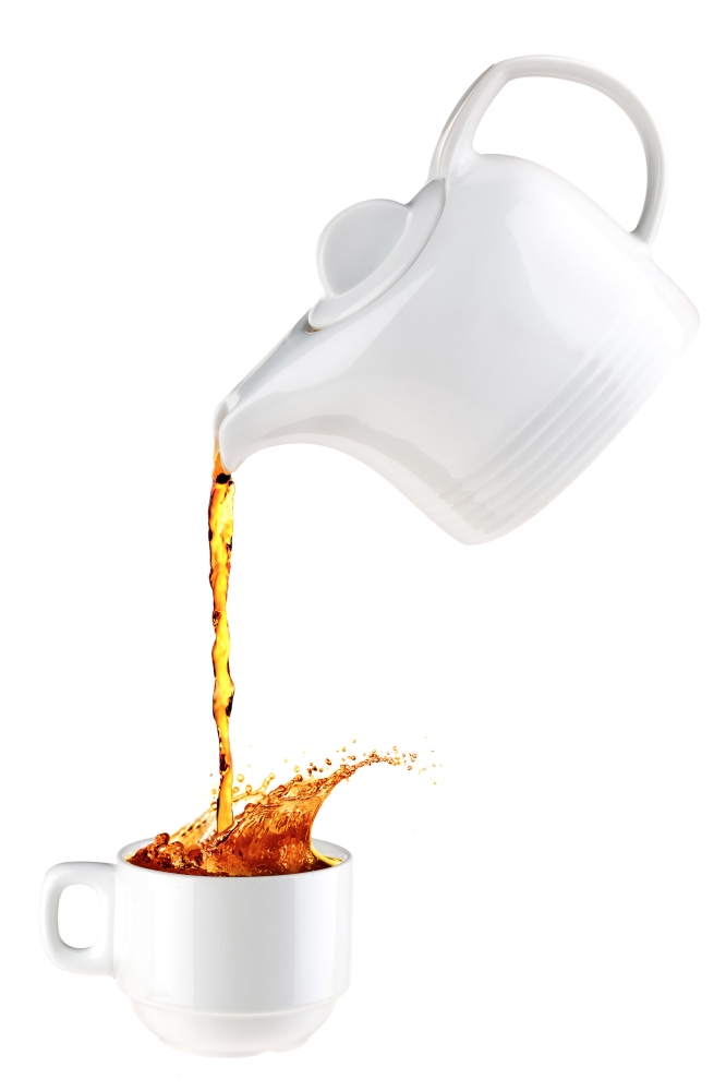 Teapot pouring tea in a white mug.