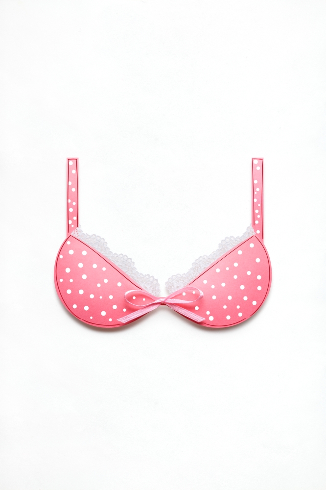 Creative concept photo of a bra with a bow made of paper on white background.