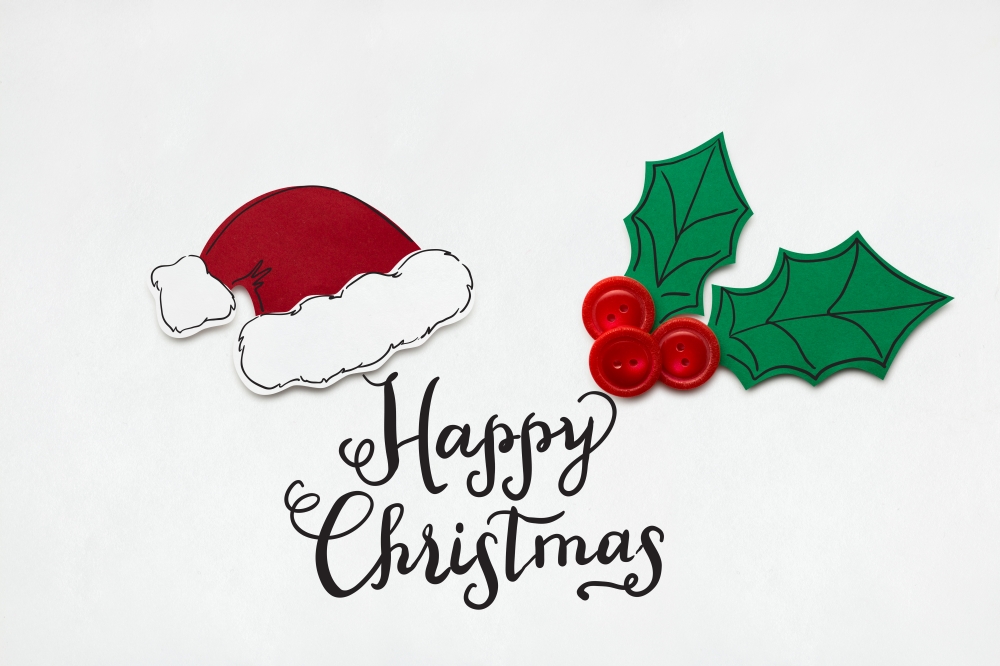 Creative photo of santas hat and holly berry made  of paper on white background.