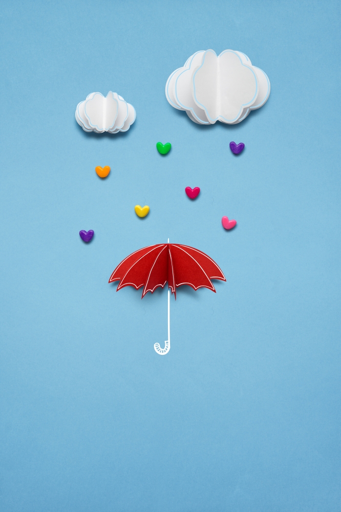 Creative valentines concept photo of umbrella with hearts raining down on white background.