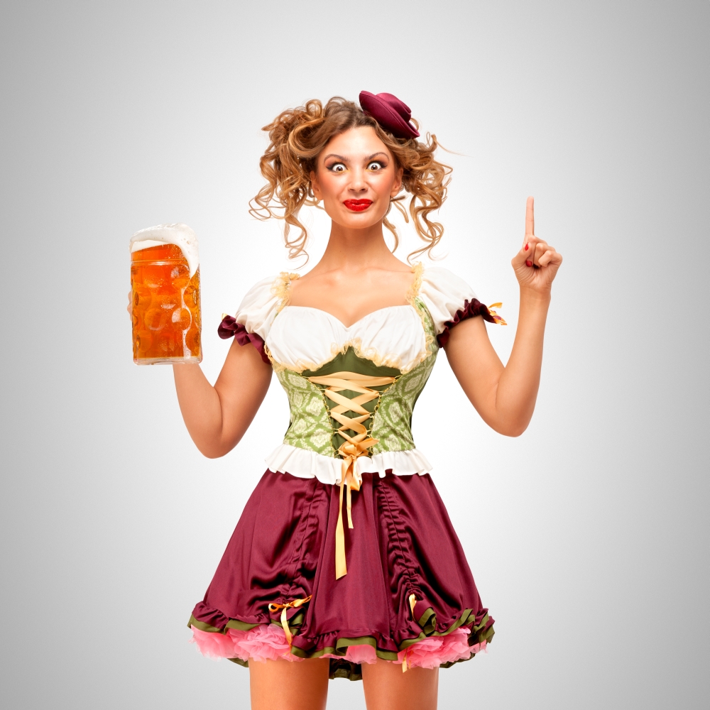 Beautiful Oktoberfest waitress wearing a traditional Bavarian dress dirndl holding a beer mug, and coming up with idea on grey background.