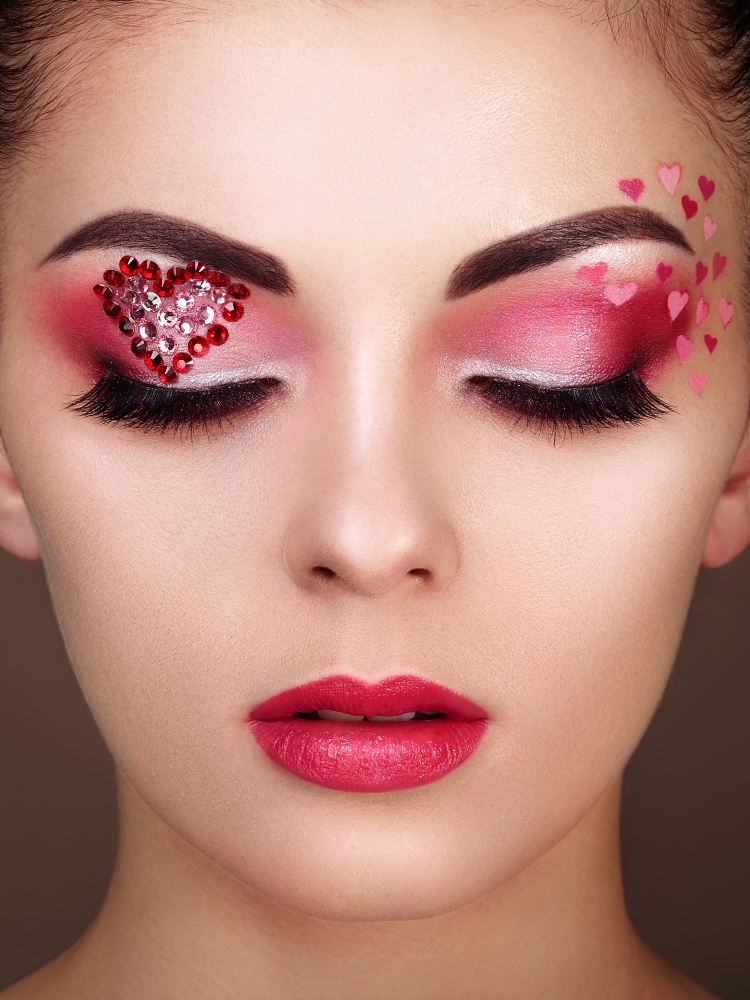 Face of beautiful woman with holiday makeup heart. Beauty fashion. Lips in red lipstick. Eyelashes. Cosmetic Eyeshadow. Makeup detail