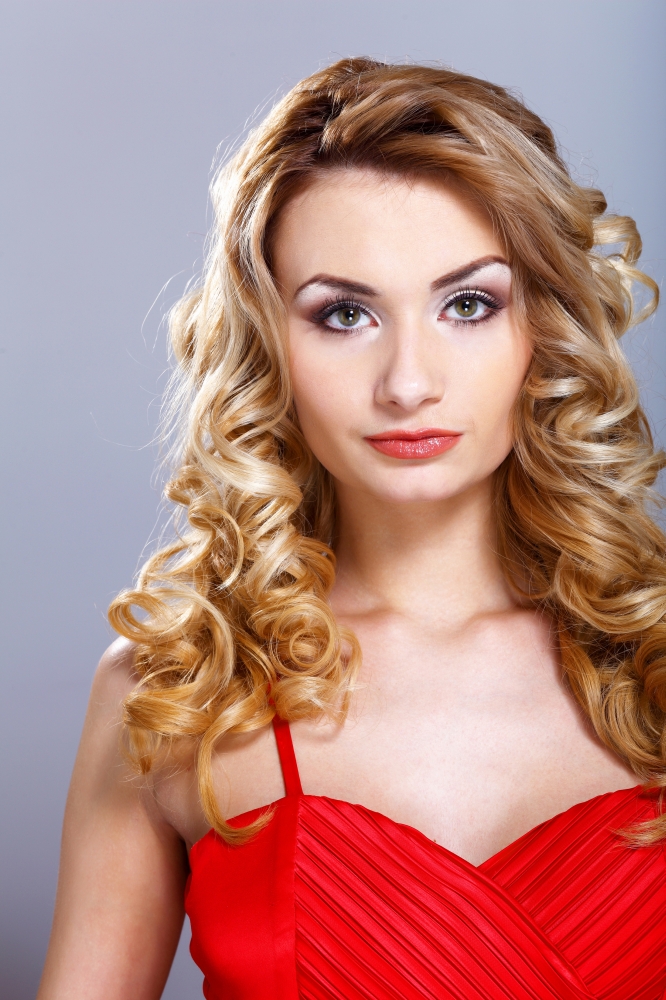 Portrait of a beautiful  young woman in red dress with curly hair