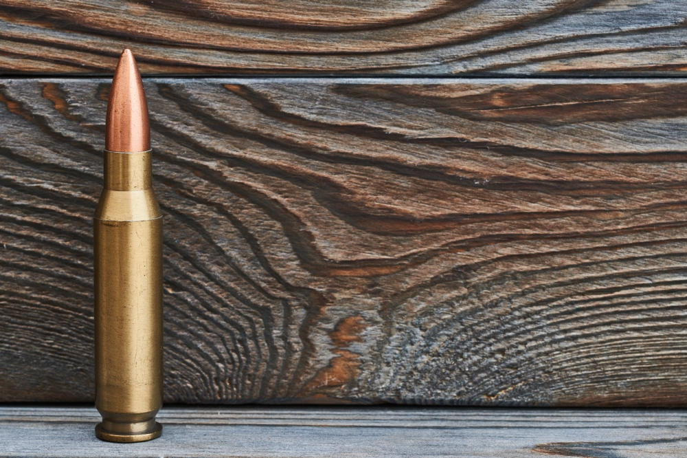Full metal jacket bullet. Full metal jacket bullet on wooden background with copy space