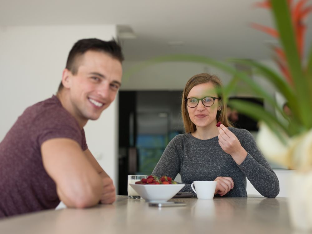 young beautiful handsome couple enjoying morning coffee and strawberries in their luxurious home villa