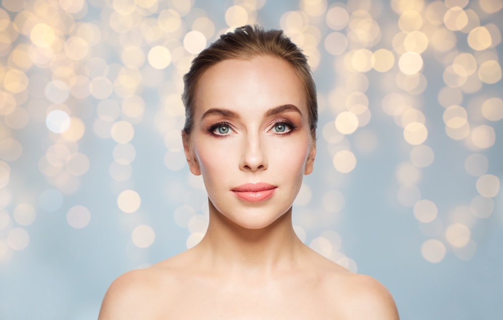 beauty, people, holidays and skin care concept - beautiful young woman face over lights background