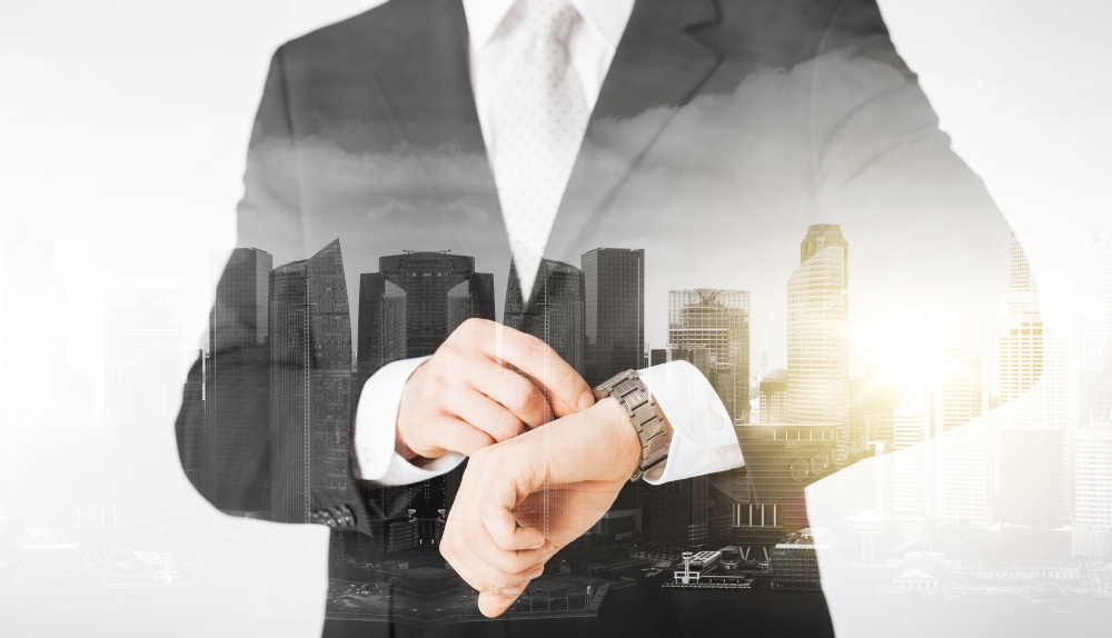 people, business and time concept - close up of businessman with wristwatch over city with double exposure. close up of businessman with wristwatch