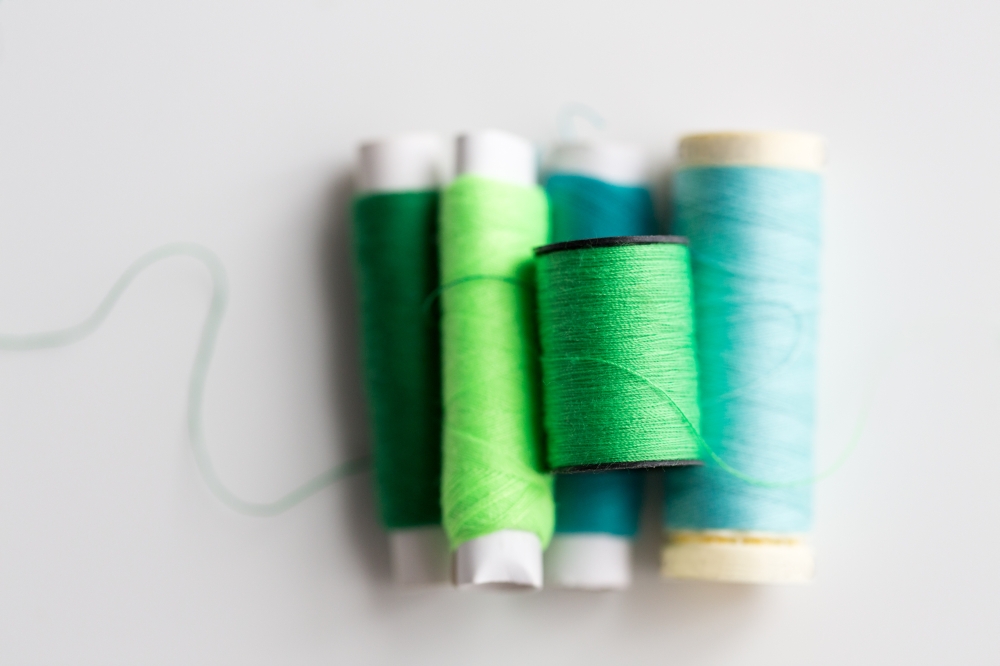 needlework, craft, sewing and tailoring concept - green and blue thread spools on table. green and blue thread spools on table