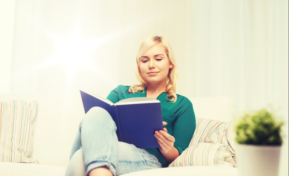 leisure, literature and people concept - smiling woman reading book at home. smiling woman reading book at home
