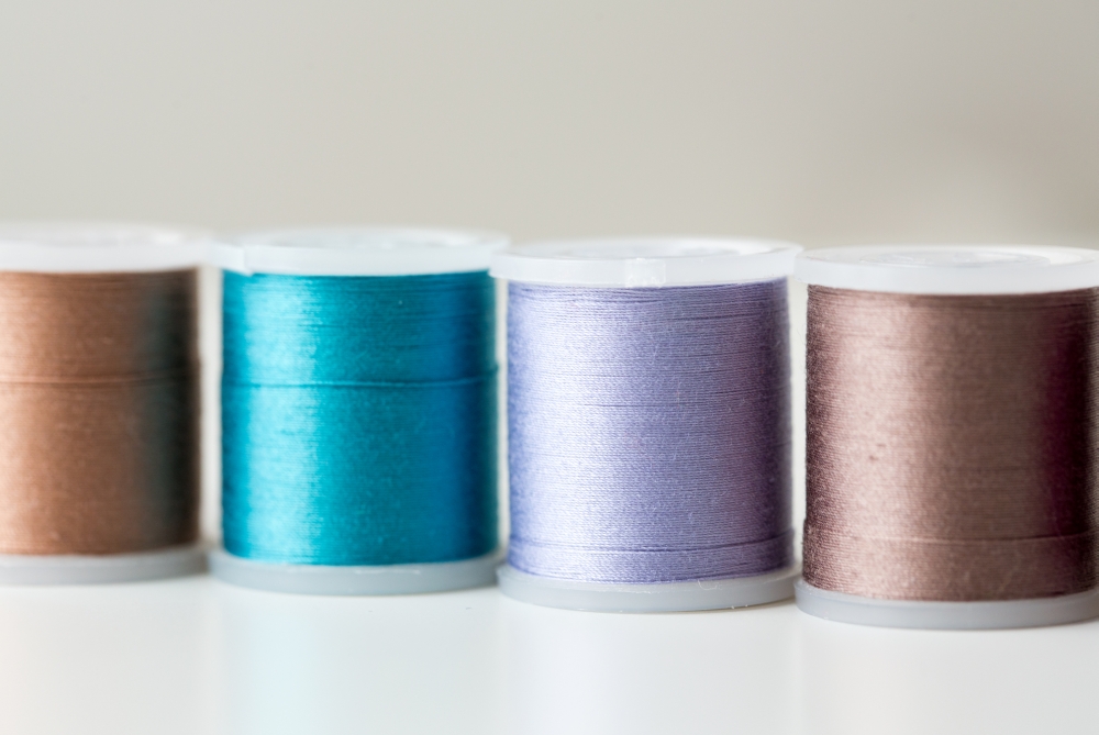 needlework, craft, sewing and tailoring concept - row of colorful thread spools on table. row of colorful thread spools on table