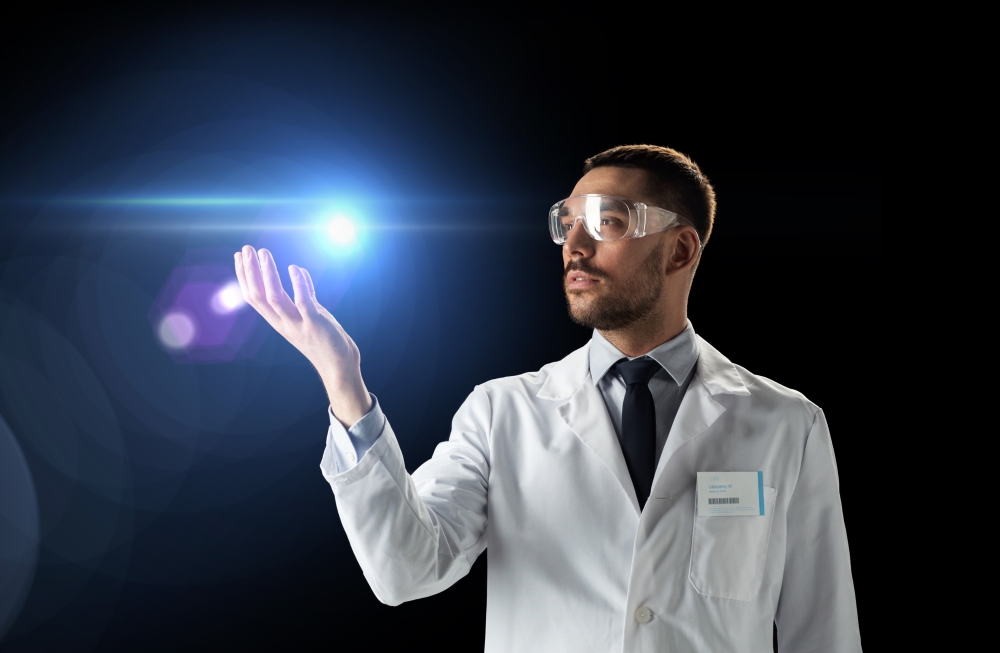 science, future technology and people concept - male doctor or scientist in white lab coat and safety glasses with laser light over black background. scientist in lab coat and goggles with laser light