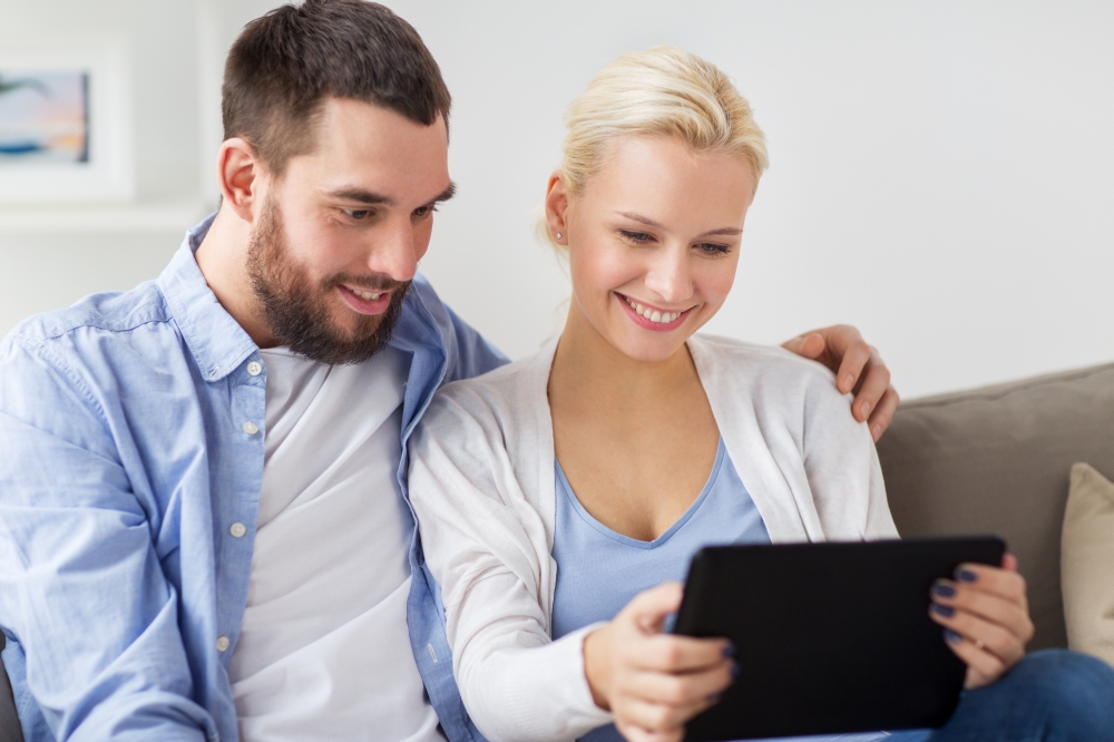 family, technology, internet and people concept - smiling happy couple with tablet pc computer at home. smiling happy couple with tablet pc at home. smiling happy couple with tablet pc at home