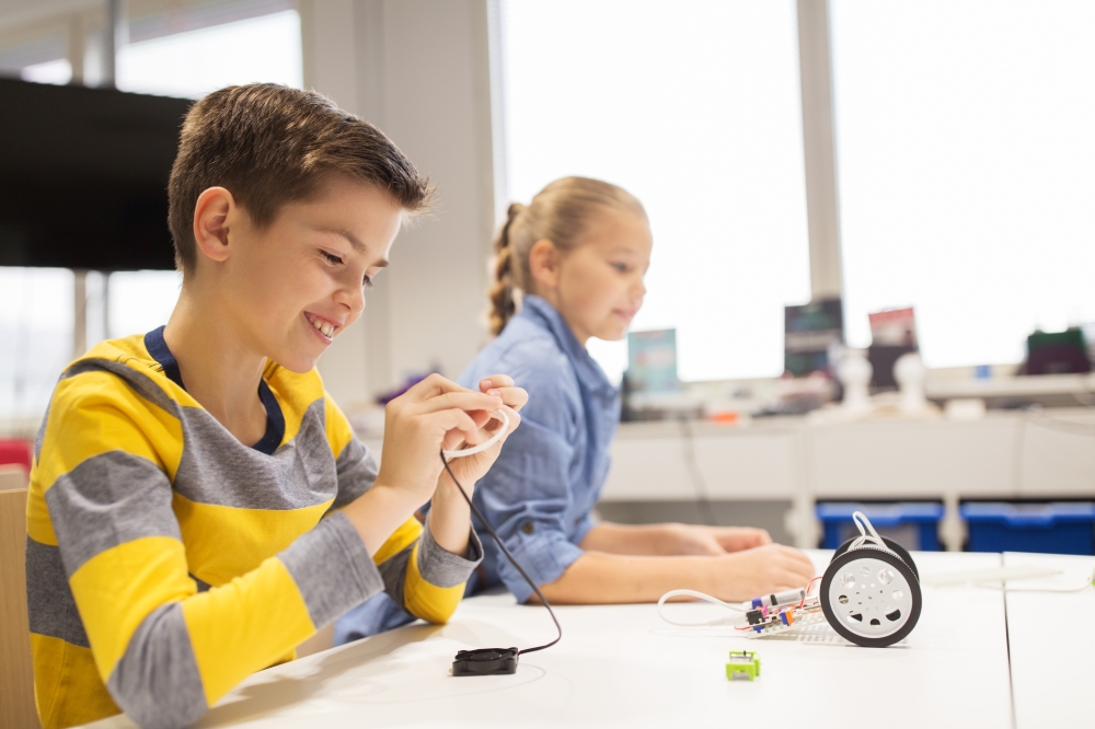 education, children, technology, science and people concept - happy kids building robots at robotics school lesson. happy children building robots at robotics school. happy children building robots at robotics school