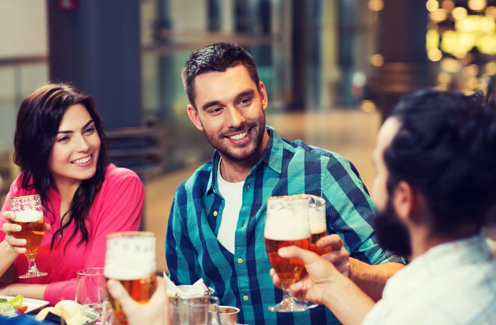 leisure, eating, food and drinks, people and holidays concept - smiling friends having dinner and drinking beer at restaurant or pub. friends dining and drinking beer at restaurant