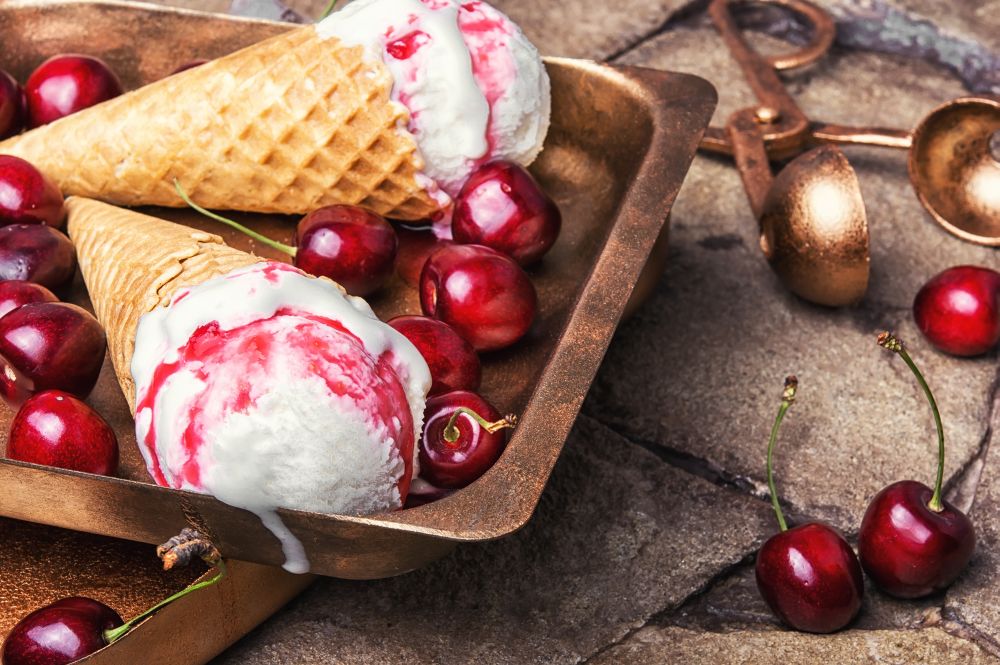 Ice-cream and spoon for ice cream. Ice cream in a waffle with cherry jam on a stylish stone background