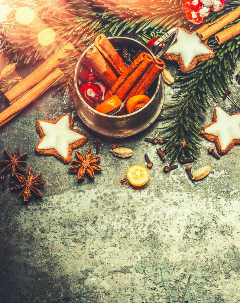Mug of mulled wine with spices and  festive Christmas decoration and bokeh lighting on rustic vintage background,top view