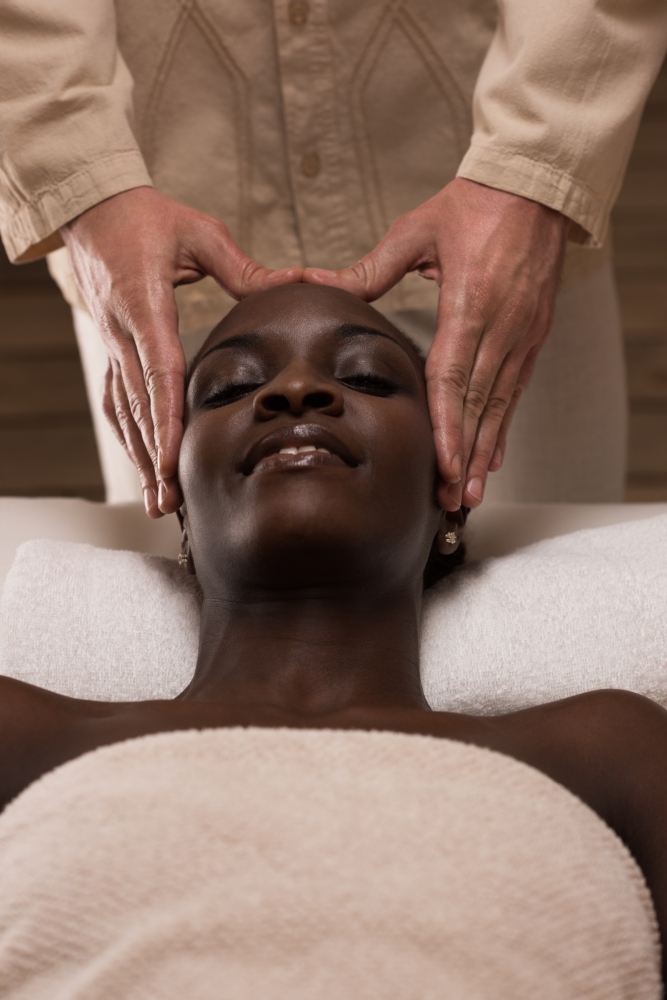 Beautiful young african woman enjoys facial massage in a luxury spa resort