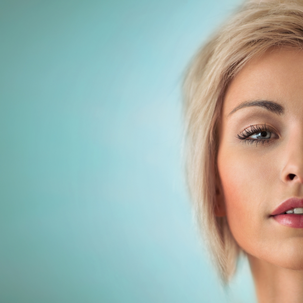 Portrait of beautiful young blond woman with clean face on blue background