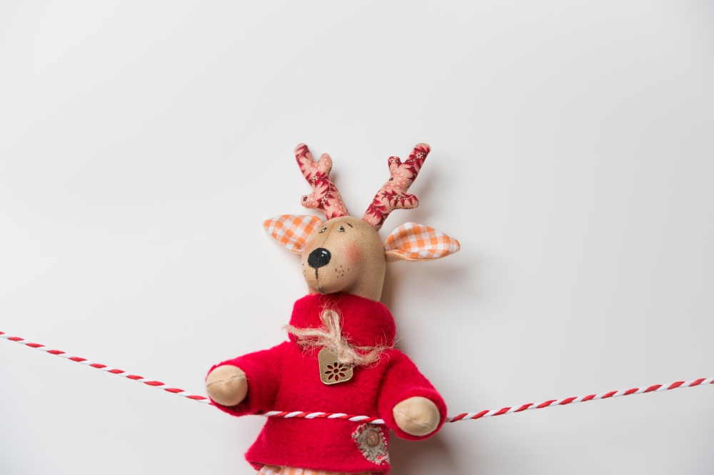 Handmade vintage Christmas deer hanging on a ribbon on white background with copyspace