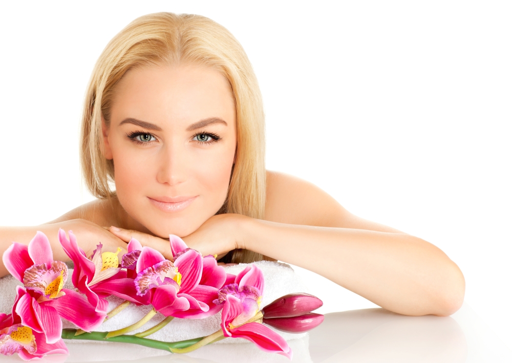 Image of happy beautiful adult girl in spa salon, attractive blonde female enjoying dayspa, pretty woman isolated on white background with pink orchid flowers, healthy lifestyle, zen and spa concept