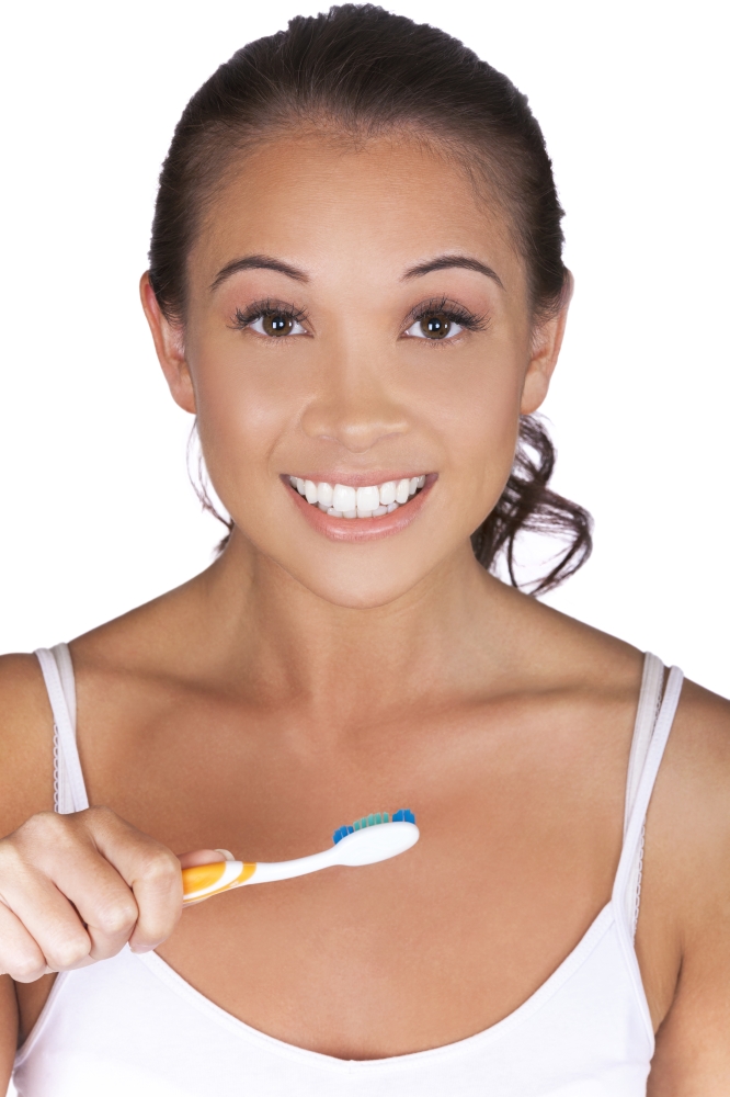 Asian Eurasian girl or young woman brushing her teeth using toothbrush and smiling