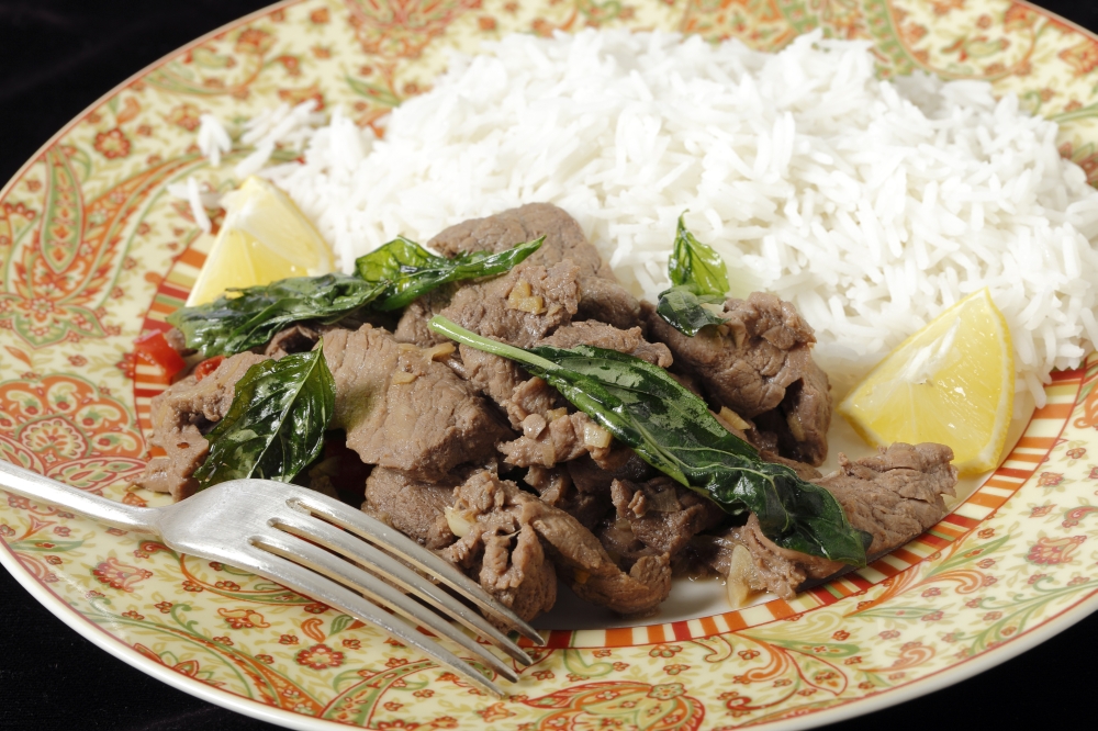 Chilli beef with crispy fried basil leaves, served with white basmati rice and lemon wedges.