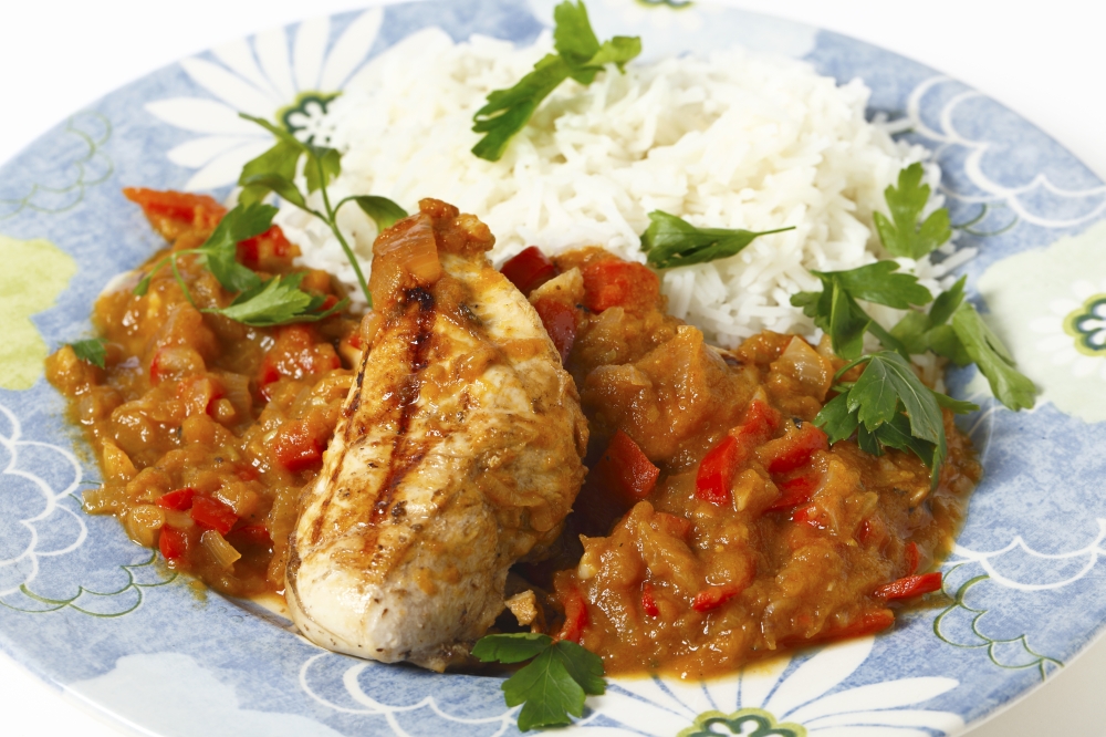 Grilled marinaded chicken served with a spice tomato and red capsicum salsa, in the Caribbean style, and white rice, all garnished with parsley.