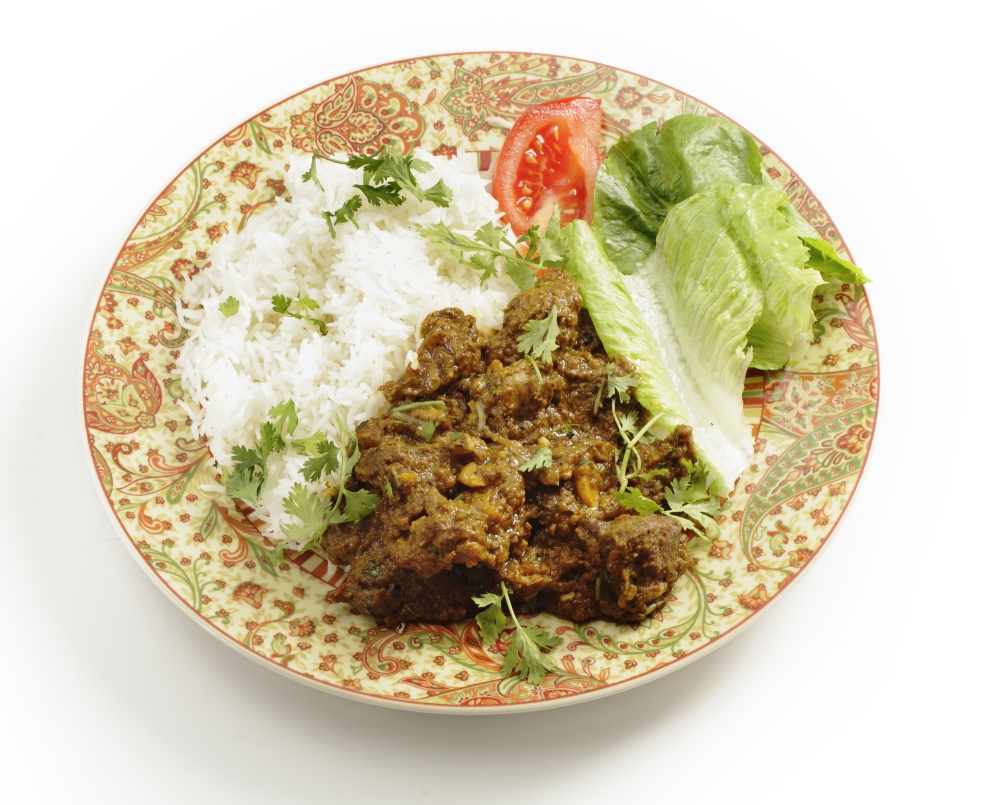 Lamb or "ghosht" dry fried curry in the Pakistani or north Indian style, served with basmati rice garnished with coriander leaves, and a lettuce and tomato salad.