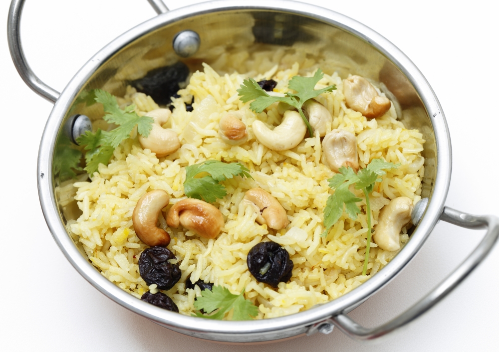 Raisin and cashew pilaf, made with basmati rice and garnished with coriander leaves, served in a traditional indian kadai dish