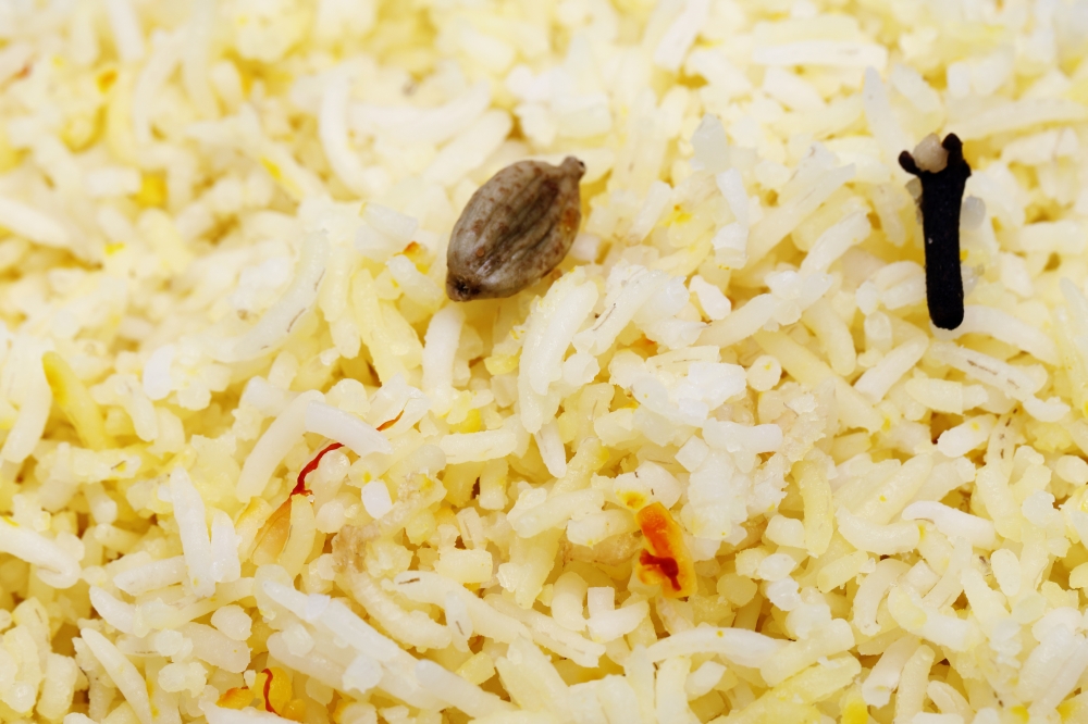 High magnification "macro" photo of saffron rice, showing a cardamom pod and a clove used while cooking the dish, together with strands of saffron.