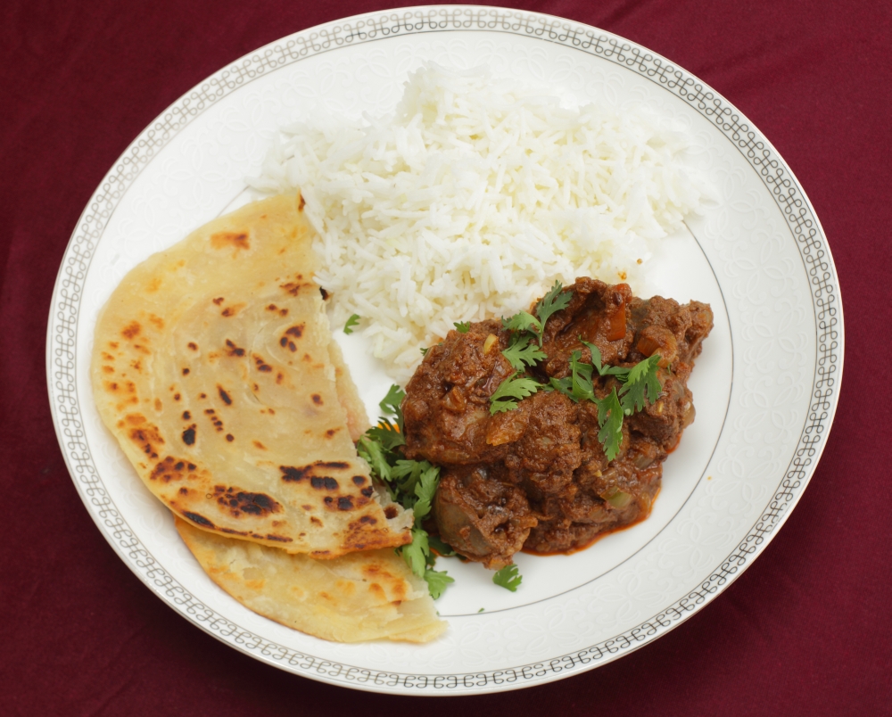 A kidney masala bhuna-type curry served with rice and paratha bread, garnished with coriander leaves