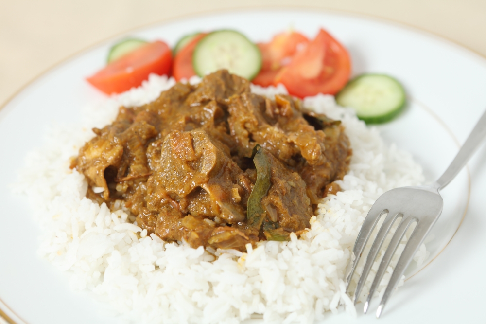 Lamb rogan josh, with basmati rice and a salad of tomato and cucumber. The lamb, on the bone is in a spicy tomato sauce.