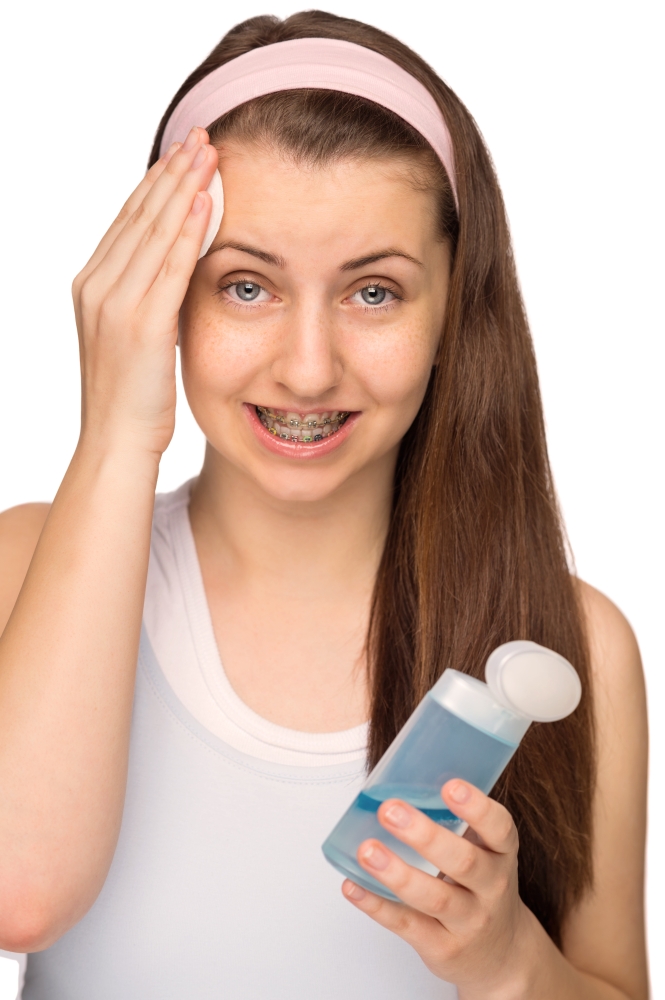 Girl with braces cleaning face with cotton pad isolated