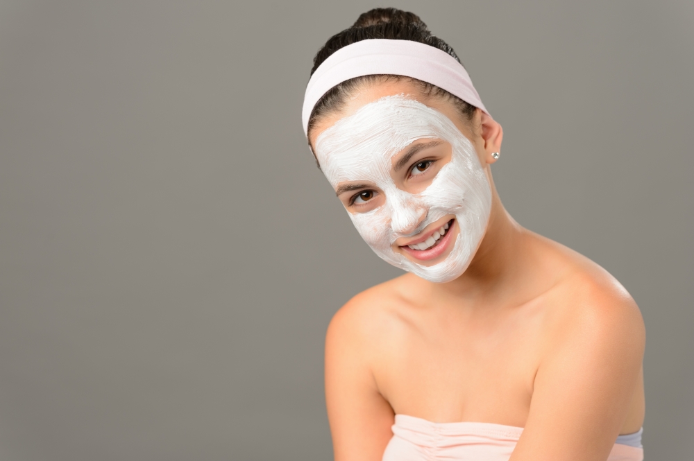 Smiling teenage girl cosmetics mask skin beauty on gray background