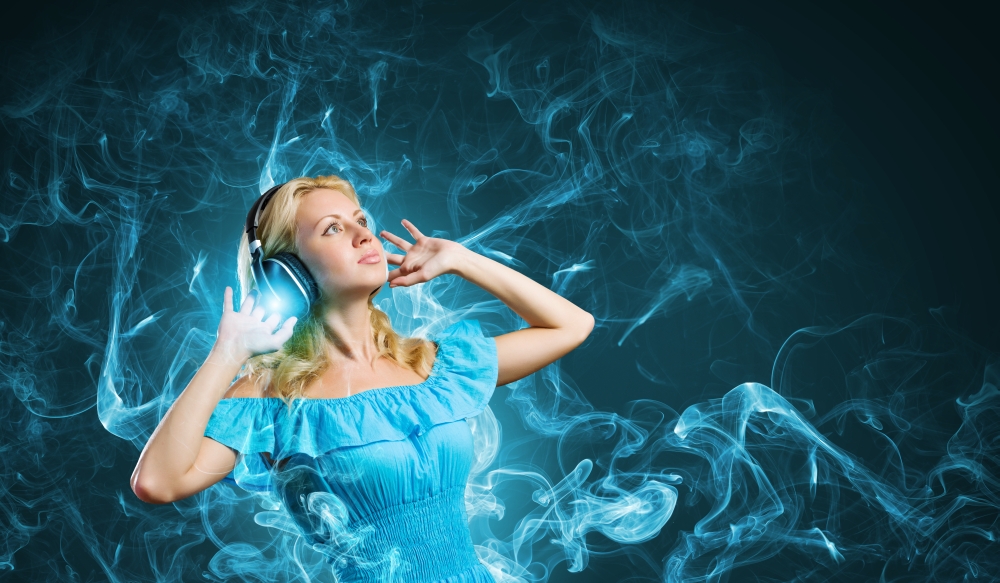 Music lover. Young blond girl in blue dress listening music