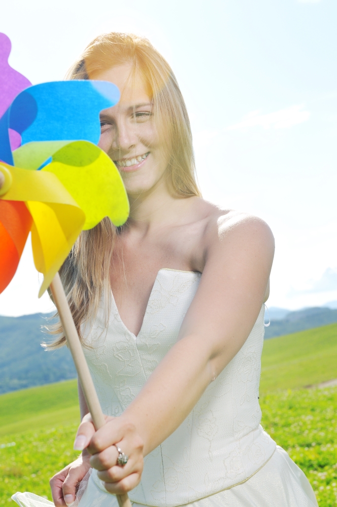 happy young beautiful bride after wedding ceremony event have fun outdoor on meadow at sunset with windmill toy and representing smart energy