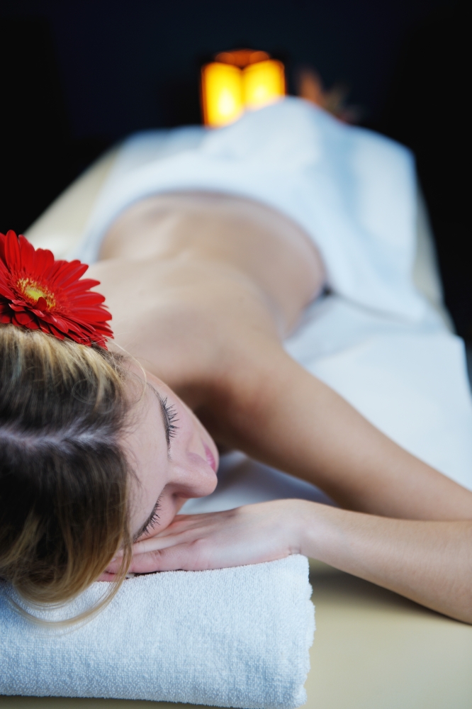 Beautiful young woman in spaand wellness. Face back and  stone massage