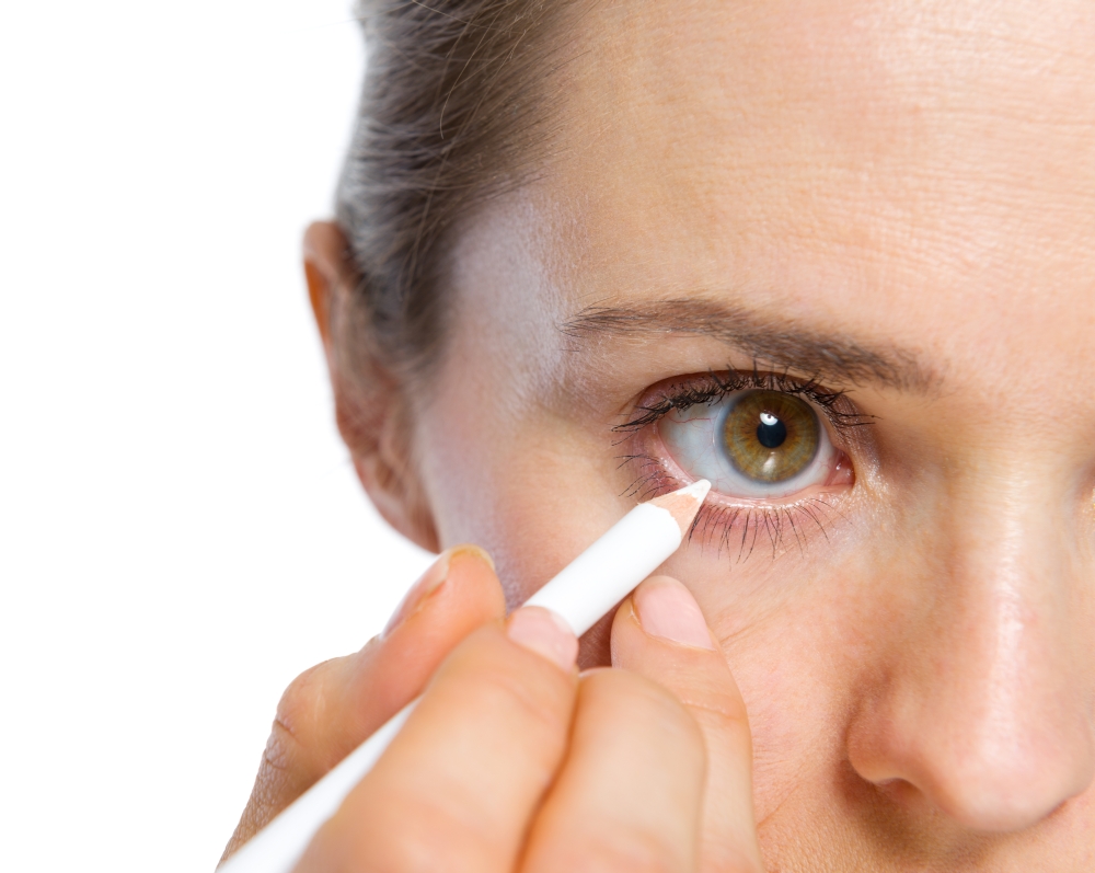 Closeup on woman using white eye liner