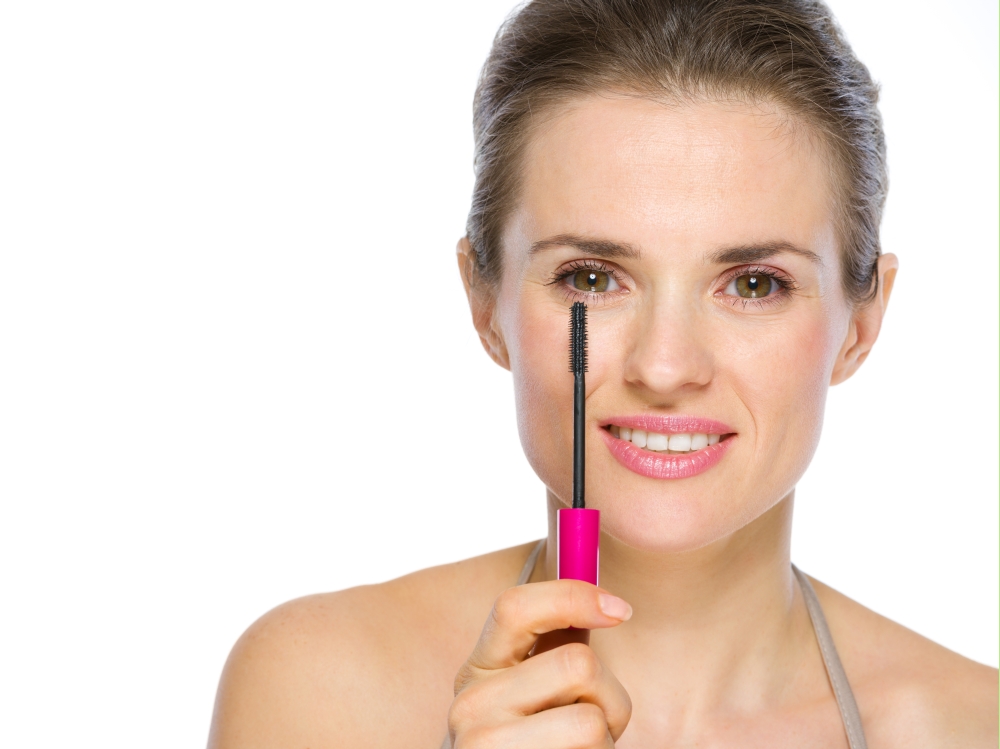 Beauty portrait of young woman holding mascara brush