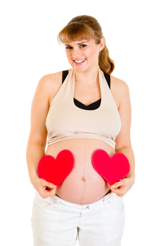 Smiling pregnant woman holding paper hearts near her belly isolated on white&#xA;