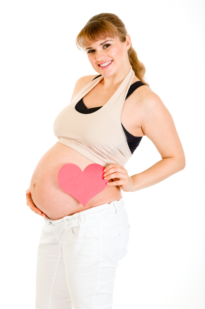 Smiling pregnant woman holding heart near her belly isolated on white&#xA;