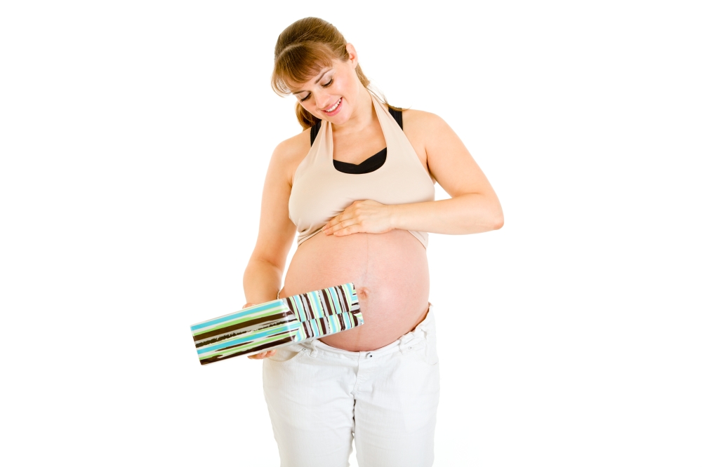 Dreaming pregnant woman holding present for her baby  isolated on white&#xA;