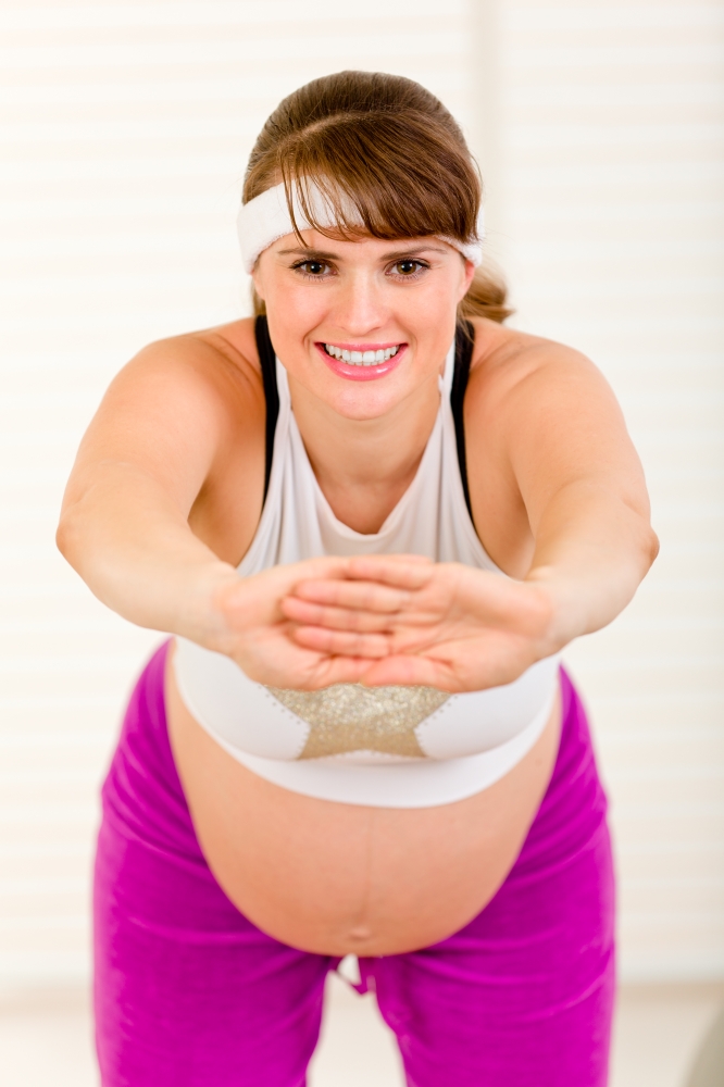 Smiling beautiful pregnant woman doing exercise at living room&#xA;