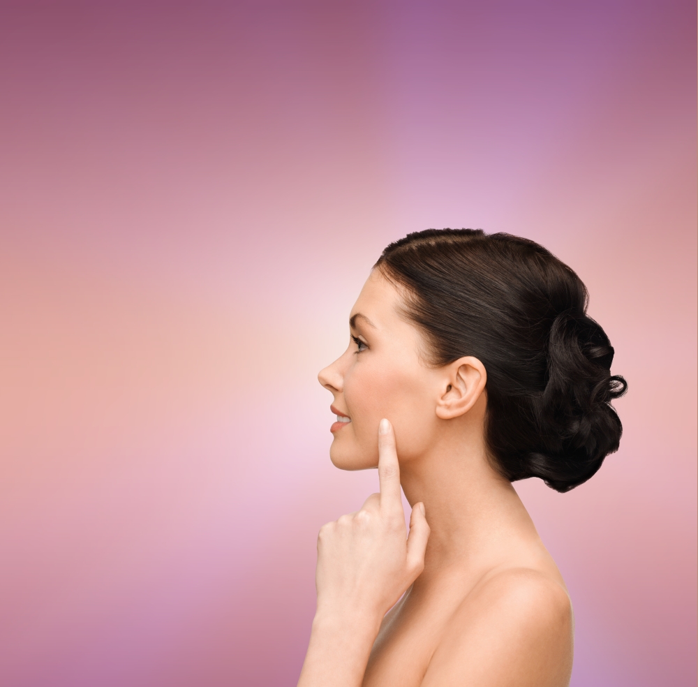 beauty, spa and health concept - smiling young woman pointing to her cheek